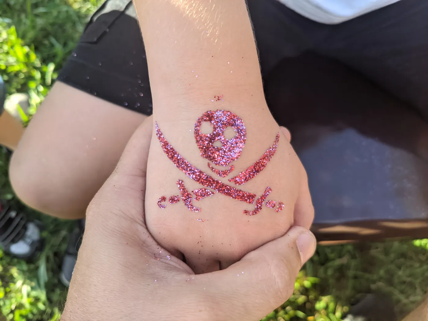 A pink glitter skull design on a hand